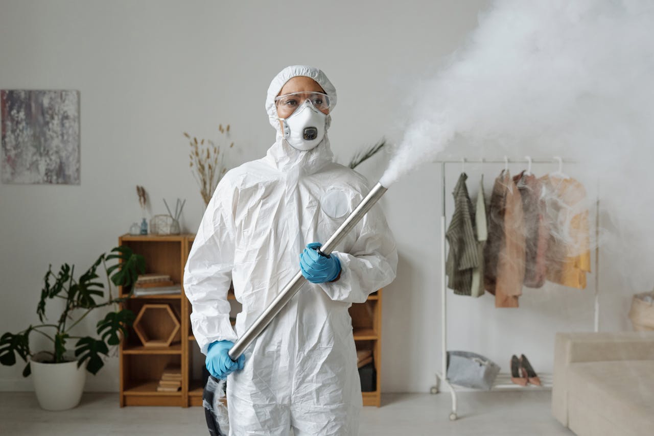 A person in full protective gear fumigates indoors for sanitization.