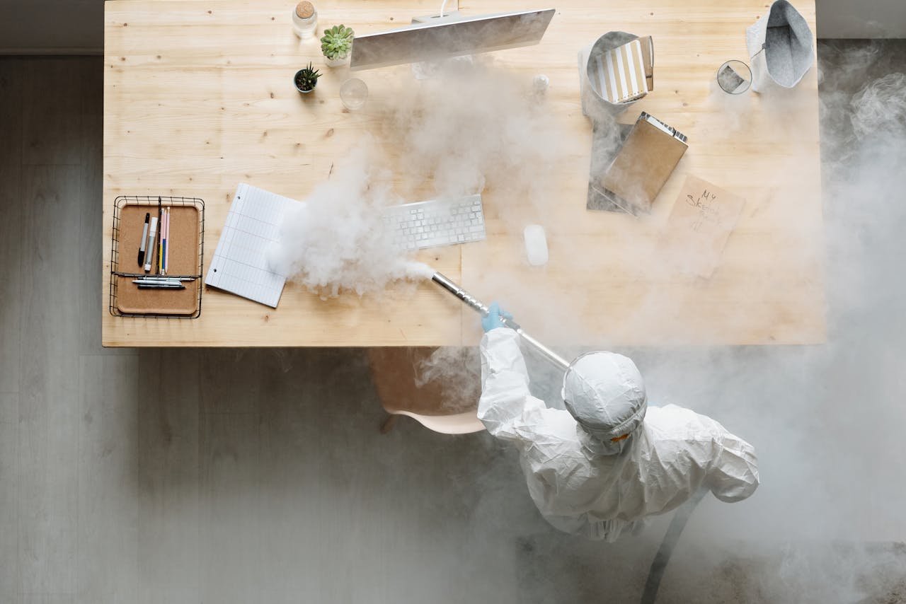 why-choose-us An individual disinfects a workspace using fumigation, wearing full protective gear for safety.